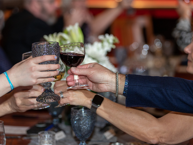 Several arms reach across a table for a toast during a formal event.