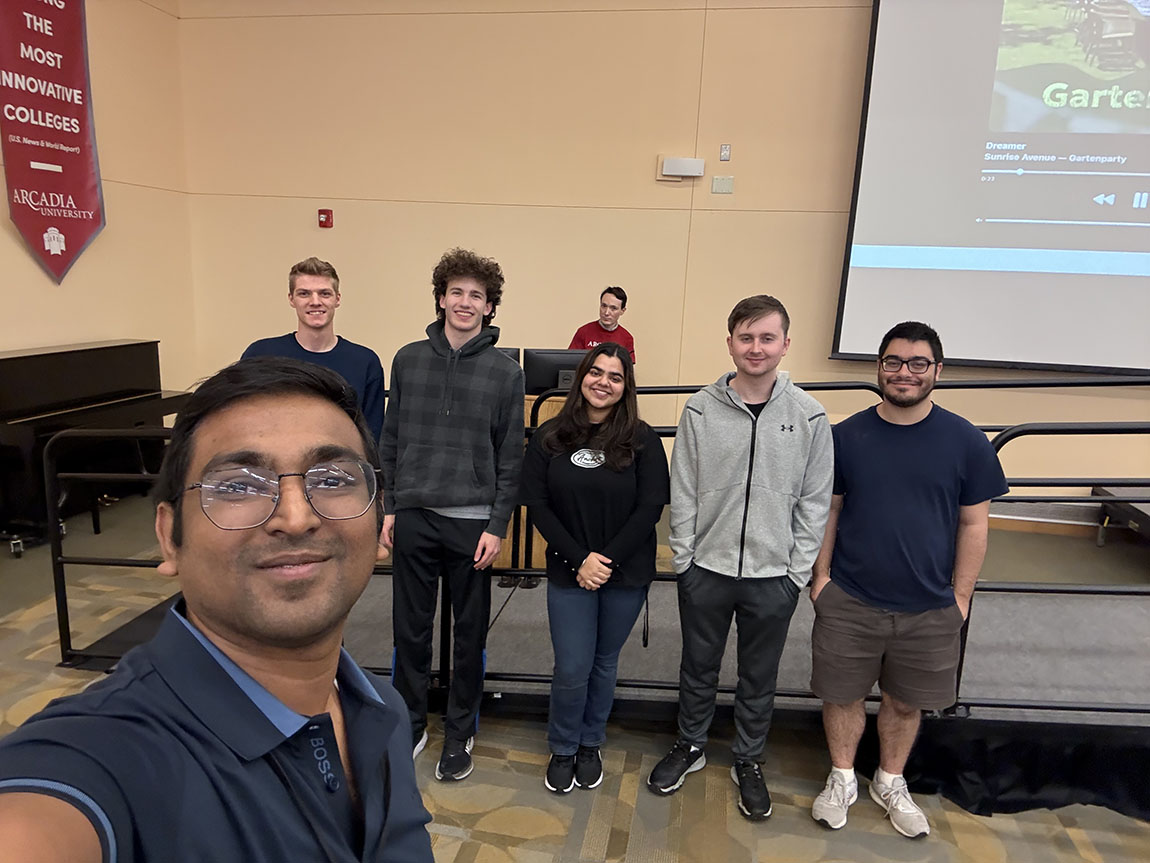 A college professor takes a selfie with a group of five students at a computer programming competition