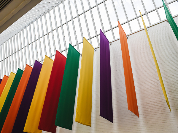 A series of colorful flags hang inside a large hallway.