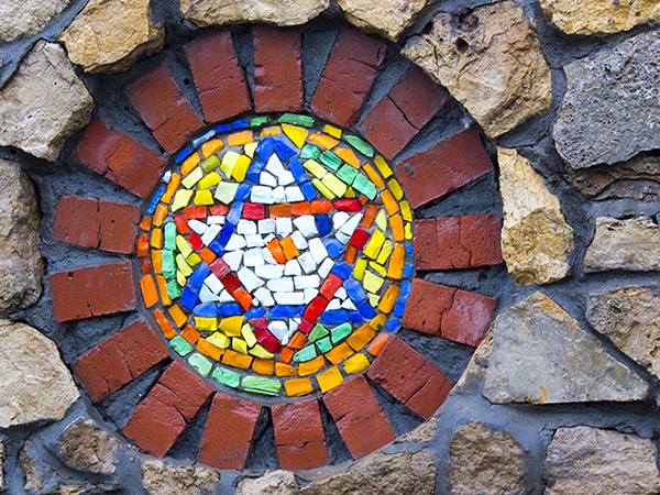 Colorful painted tiles make up an image of the Star of David, set into a stone structure.