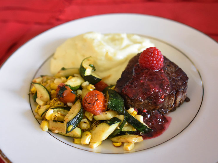 Filet mignon, roasted vegetables and mashed potatoes are arranged carefully on a dinner plate.