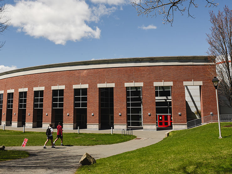 Students walk toward the Life Sports Center, a large rounded brick building, on the campus of Muhlenberg College.