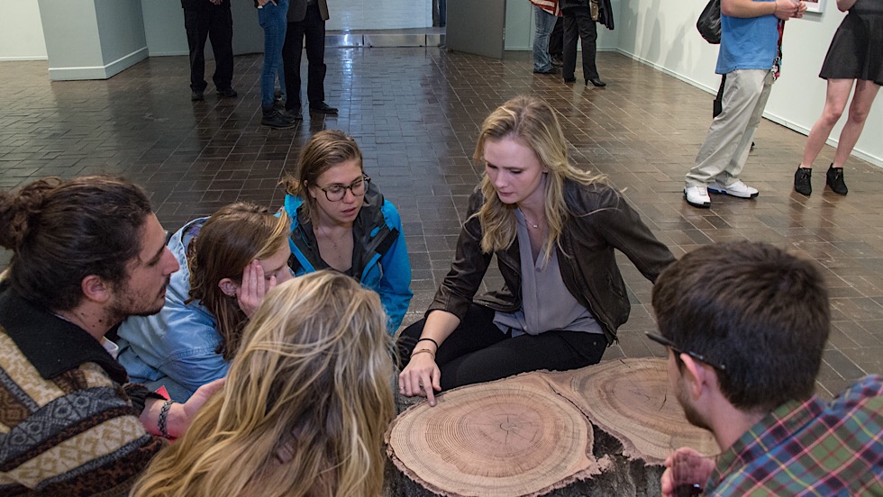 Image for Katherine Boll discusses her thesis project with classmates in the Martin Gallery during an exhibition. We believe that our students should have access to as many resources as possible in order to foster their personal, academic, and artistic growth.