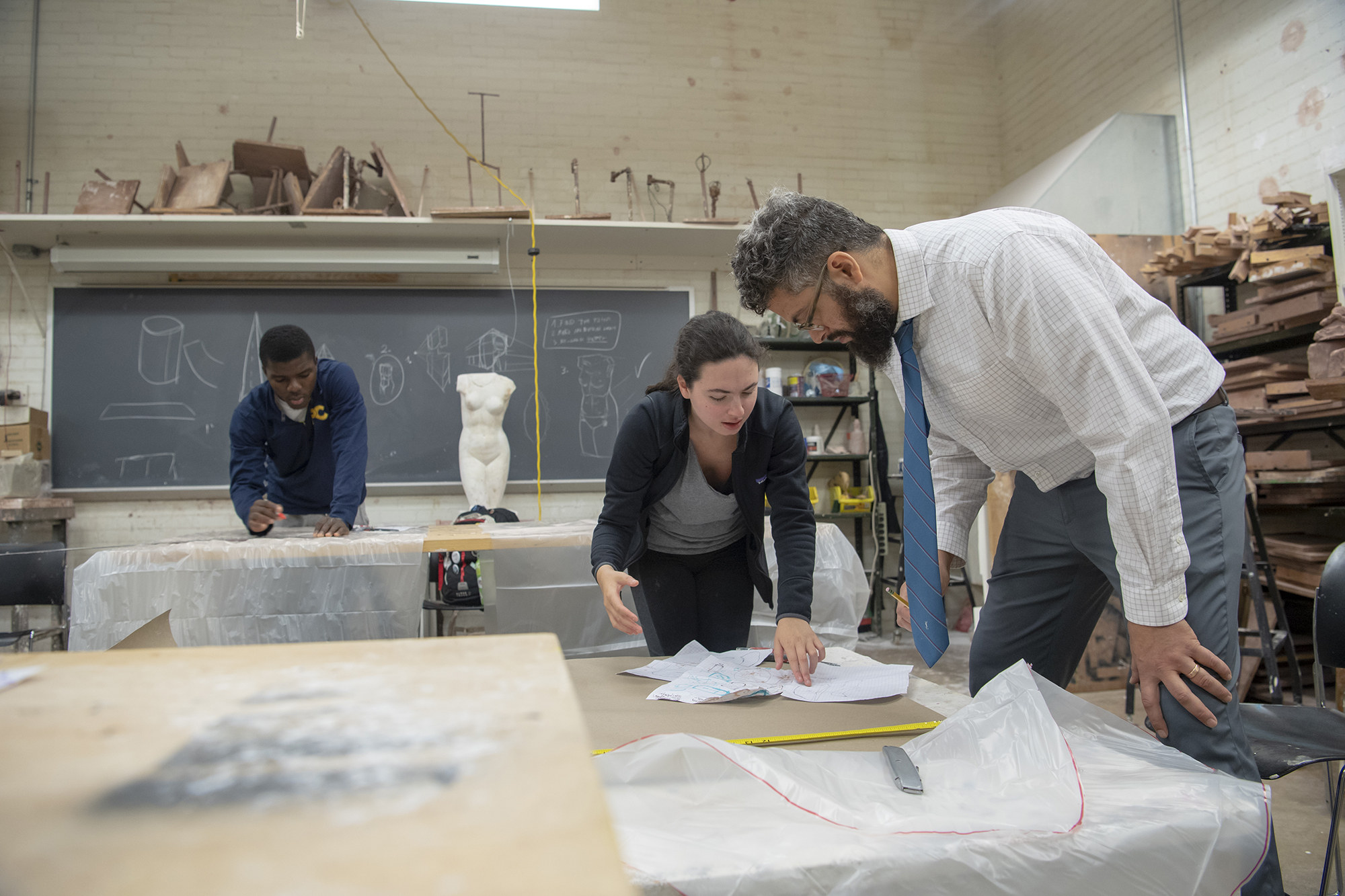 Image for Sculpture Professor Frederick Wright Jones consults with a student in a studio art class. Our faculty exhibit nationwide, and their own experiences provide insight for students who wish to pursue careers in artistic fields.