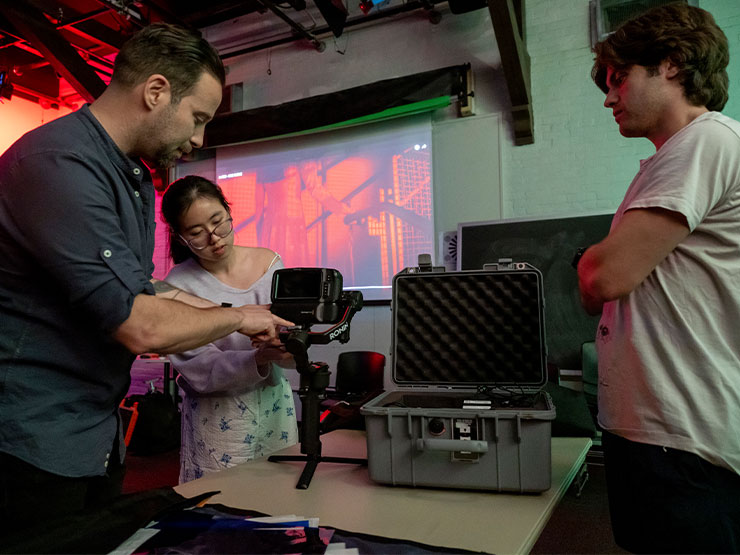 A college instructor demonstrates how to use film equipment to students in a film studio.