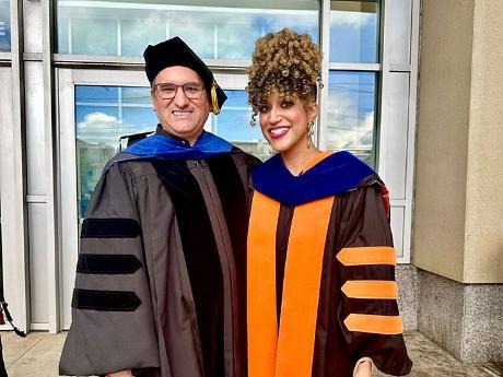 A pair of college instructors dressed in graduation regalia stand outside the PPL Center.