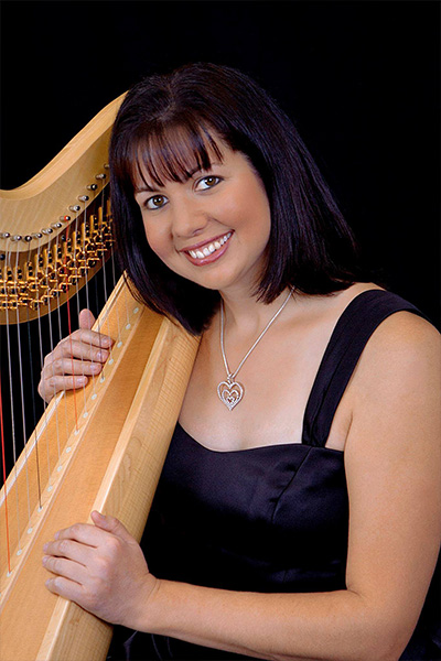 Faculty member, Jennifer Thompson, holding a harp while posed for portrait.