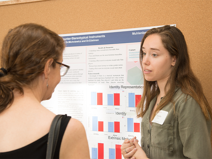 A students explains the content of a research poster to a visitor during the Muhlenberg Celebration of Scholarship.