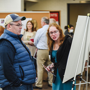 A college student explains the contents of a poster during a research poster fair.