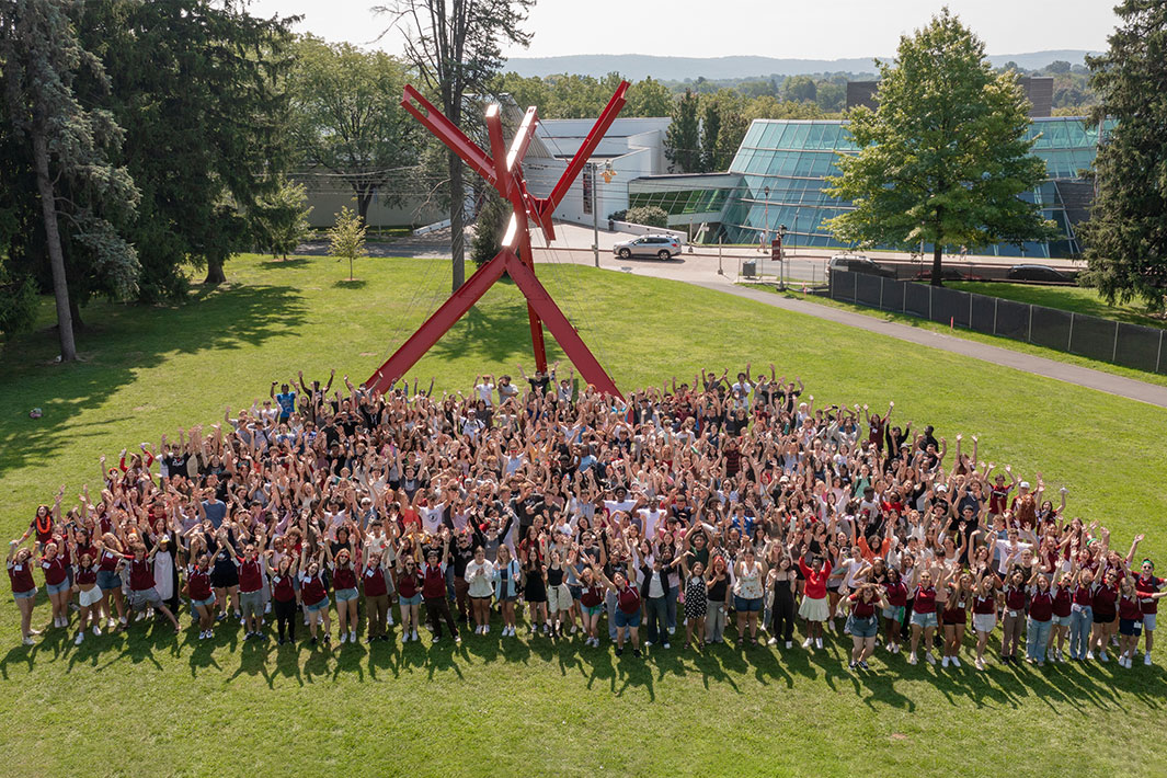 An aerial image of hundreds of students on the Muhlenberg Green, near the red modern sculpture, Victor's Lament.