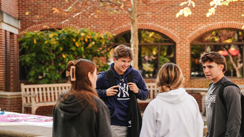 A cluster of college students chat together outdoors on the campus of Muhlenberg College.