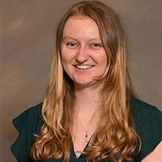 A professional portrait of a woman with long blonde hair, smiling at the camera.