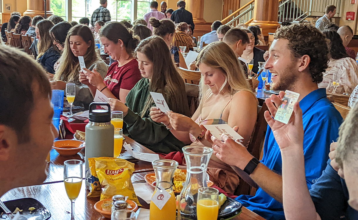 A dining hall full of students read notecards, talk with one another and eat brunch.