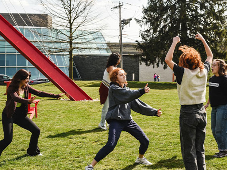 Students dance, pose and laugh on a college green.