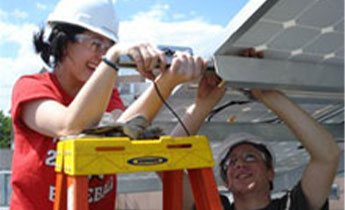 A pair of people with hardhats work on a solar panel.