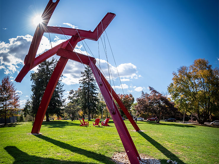 The red modern sculpture Victors Lament stands against a bright blue sky on the Muhlenberg College campus.