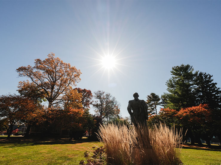 A statue of a historic Muhlenberg figure faces the sun on the Muhlenberg College green.