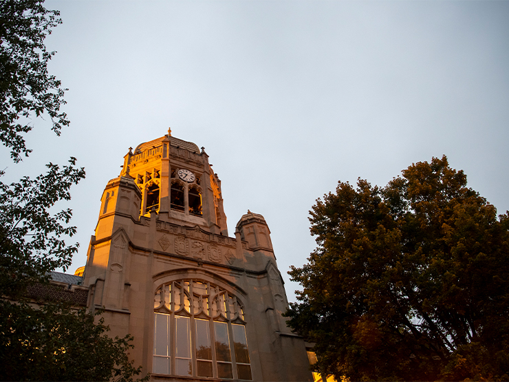 The clocktower of Haas College Center reflects the warm light of the setting sun.