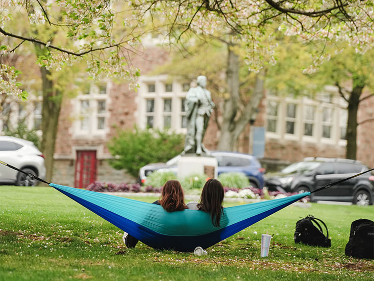 A pair of college students share a hammock under a tree on the campus of Muhlenberg College.