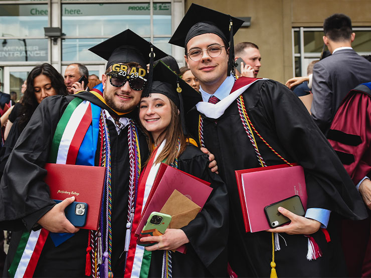 A trio of recent graduates pose together following a commencement ceremony.