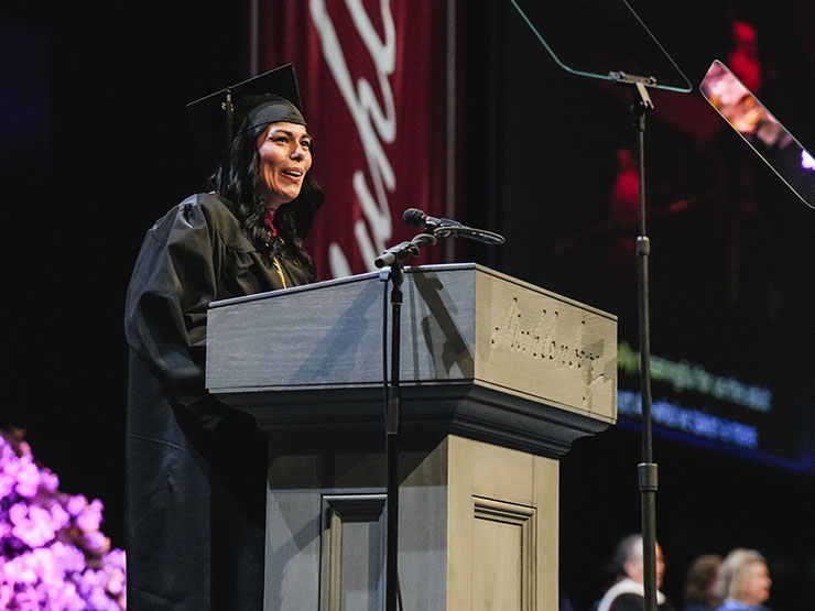 Christine Compton, recent continuing studies grad, speaks at a podium during a commencement ceremony.