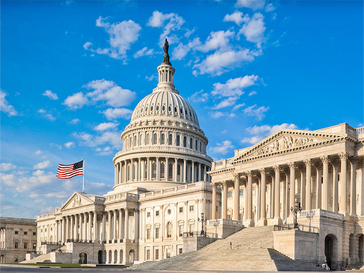 The Capitol building in Washington DC stands against a blue sky.