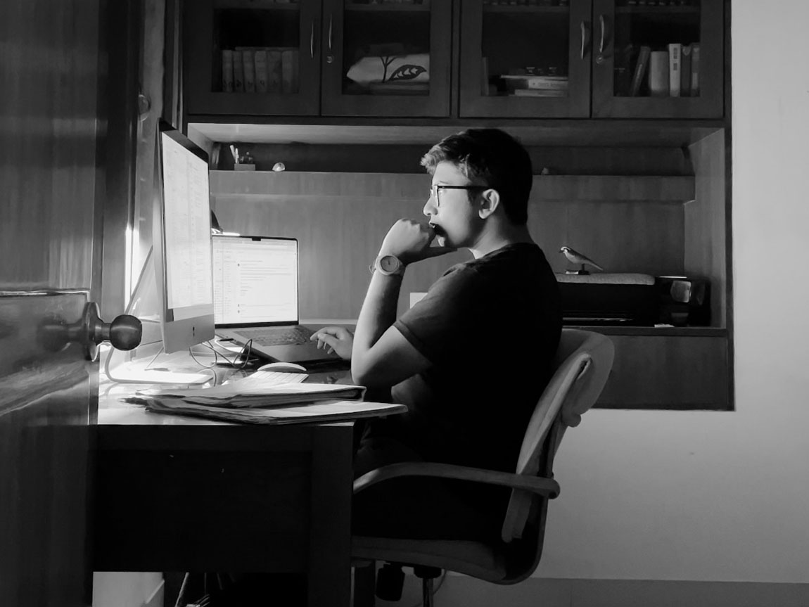 A black and white photo of a college student sitting in front of a computer