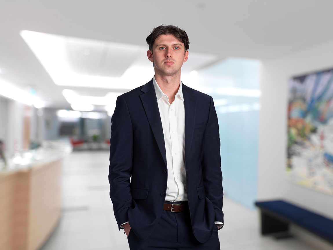 A young lawyer in a blazer and white button down shirt poses for a headshot