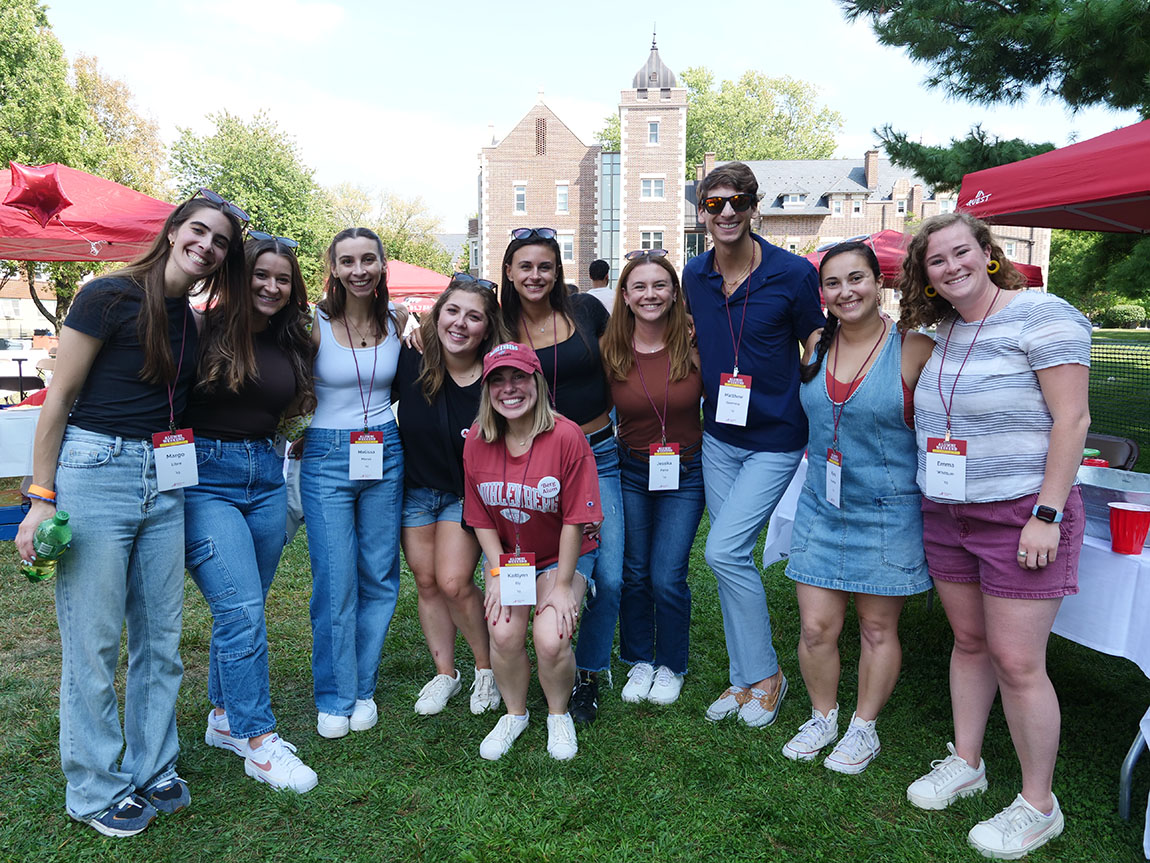 A group of young people stand outside and pose for a photo