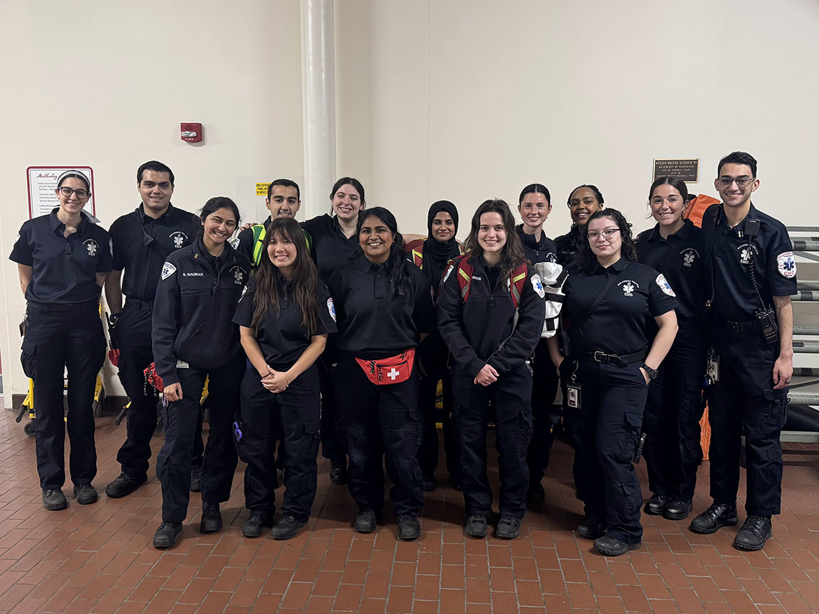 A group of college students in EMS uniforms gathers for a group photo inside the Life Sports Center