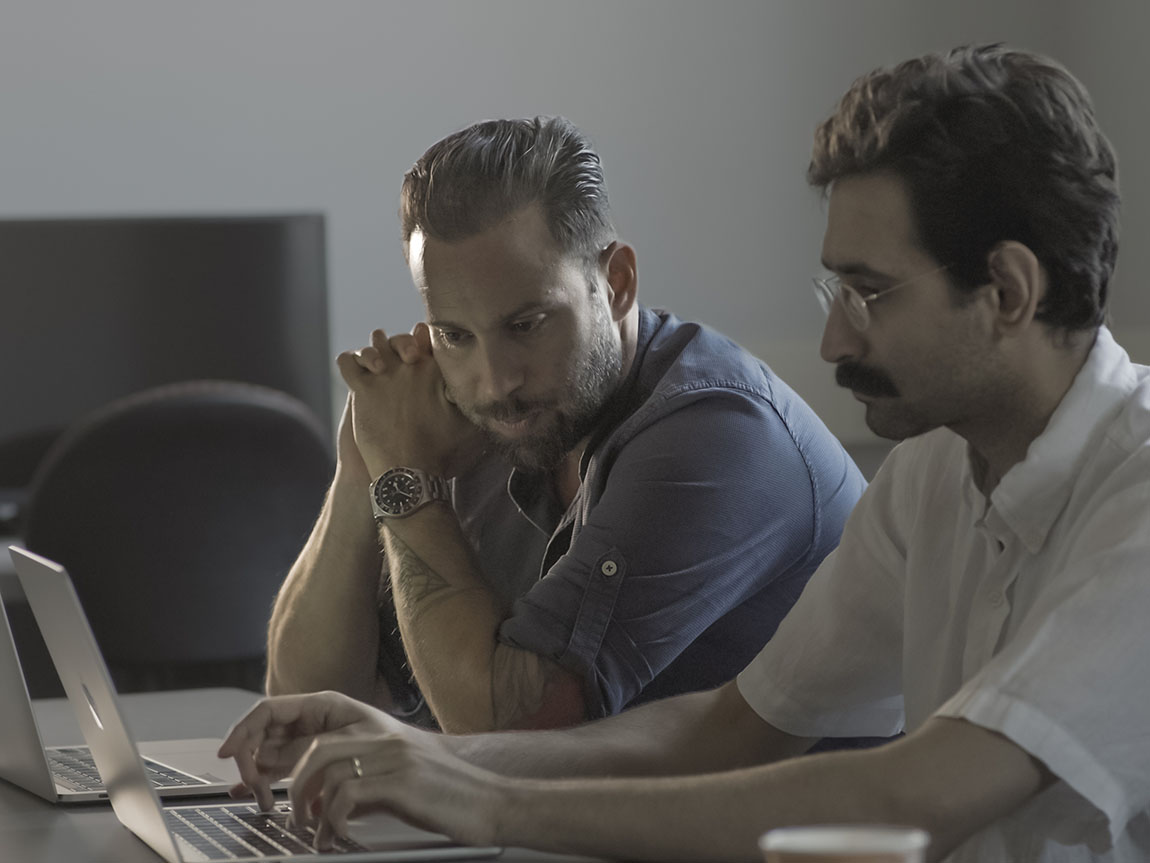 Two college professors sit together at a laptop