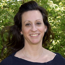 A college professor with long dark hair photographed outside