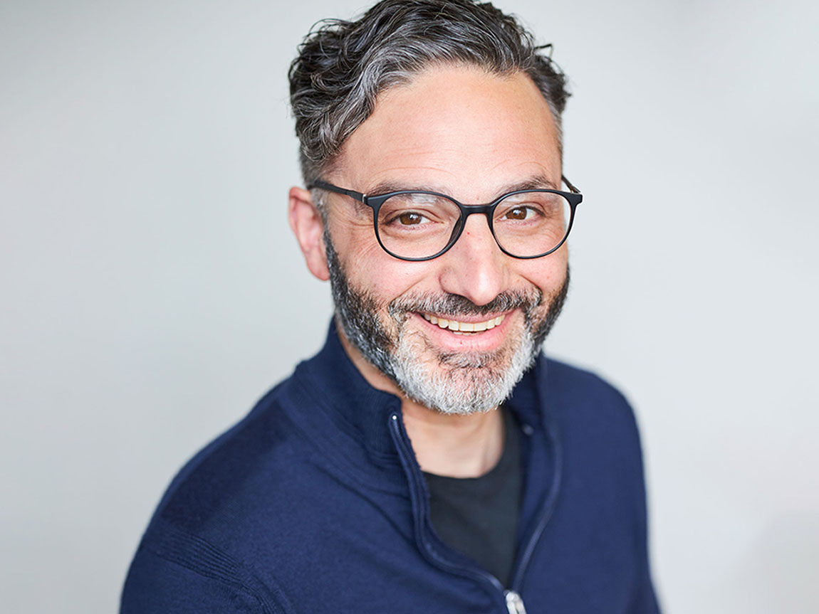 A headshot of a man with glasses and a salt and pepper beard