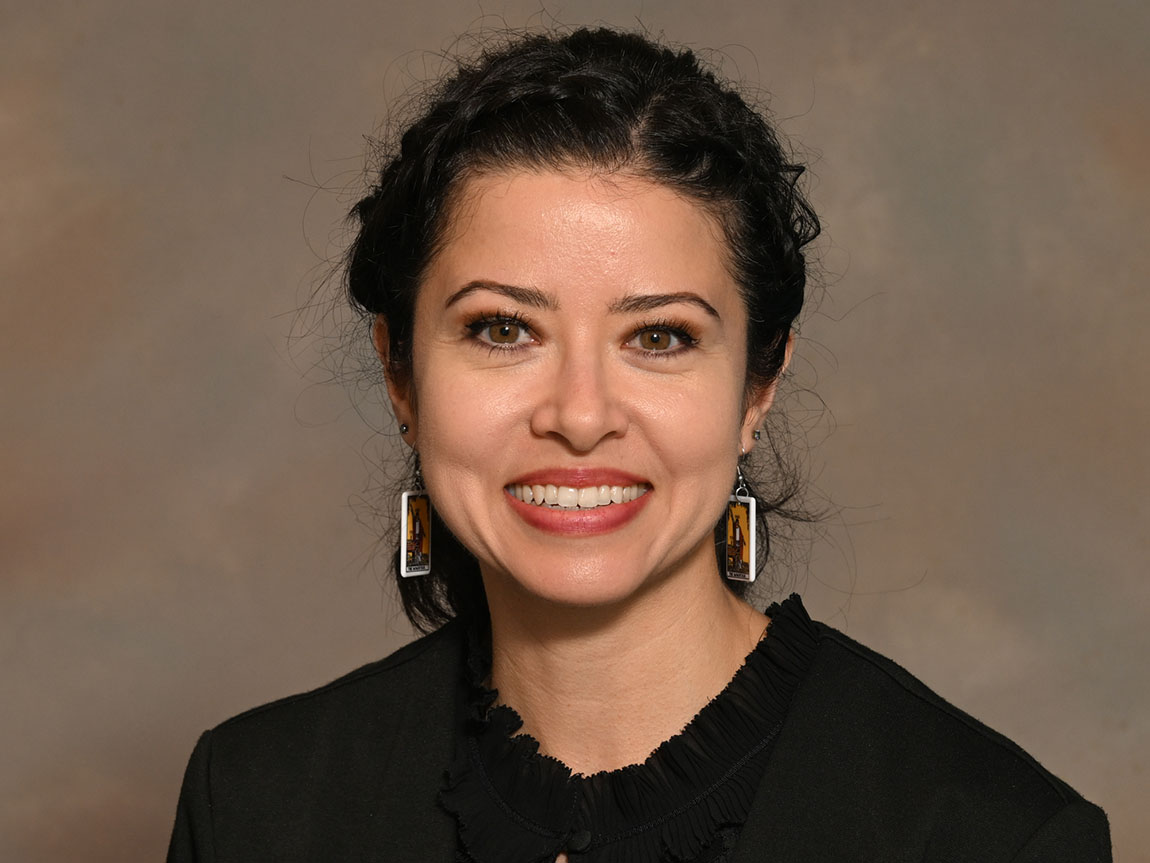 A headshot of a college professor with long dark hair