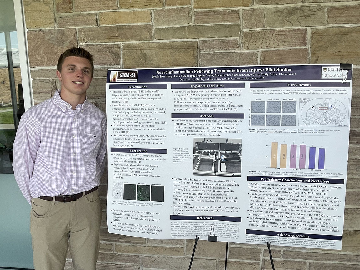 A college student stands next to a research poster