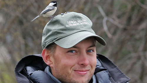 A young person wearing a hat that says Lehigh Valley Audubon Society with a bird perched on top.